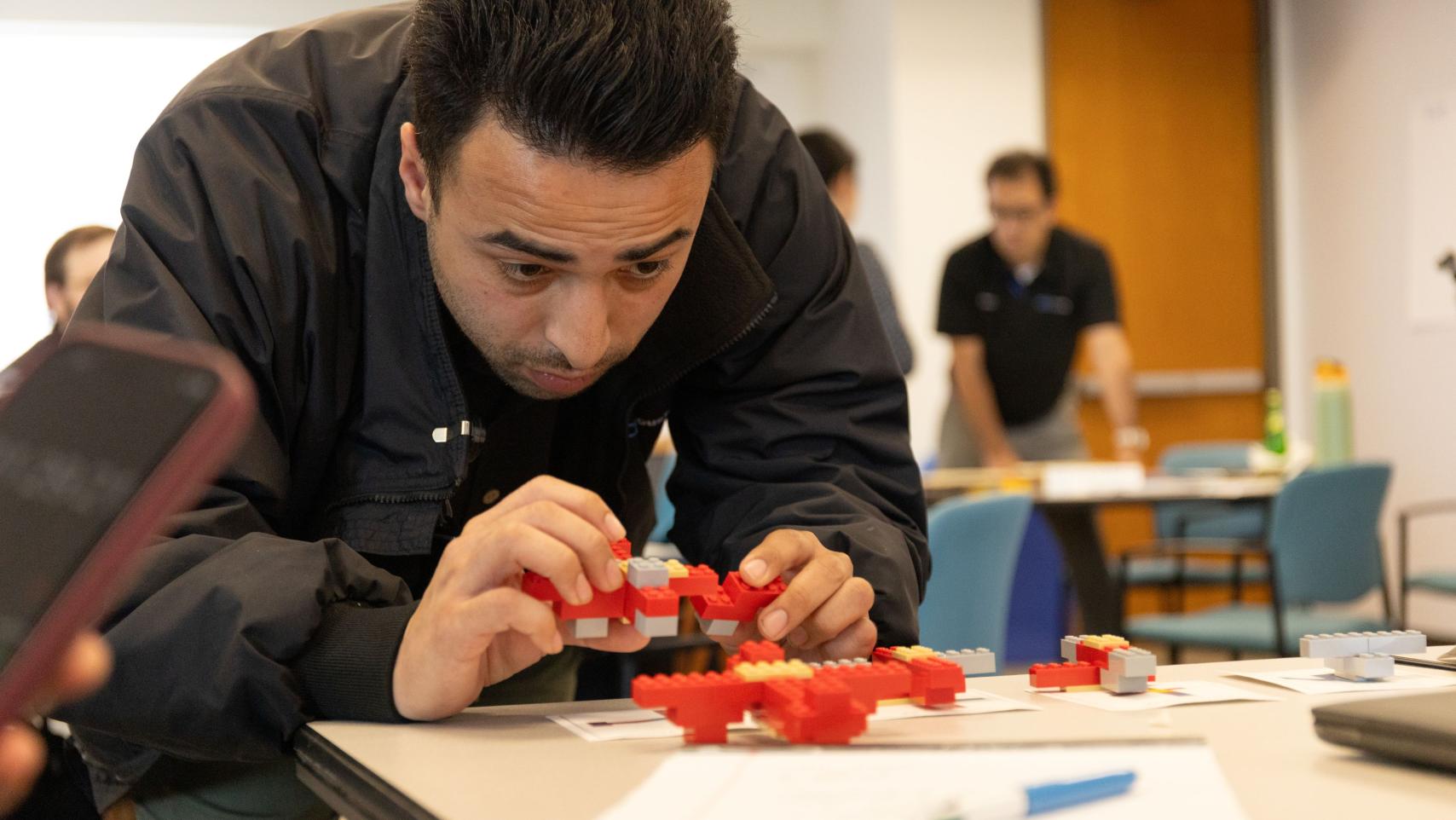 Male Lean Six Sigma participant looking at a Lego model in his hands